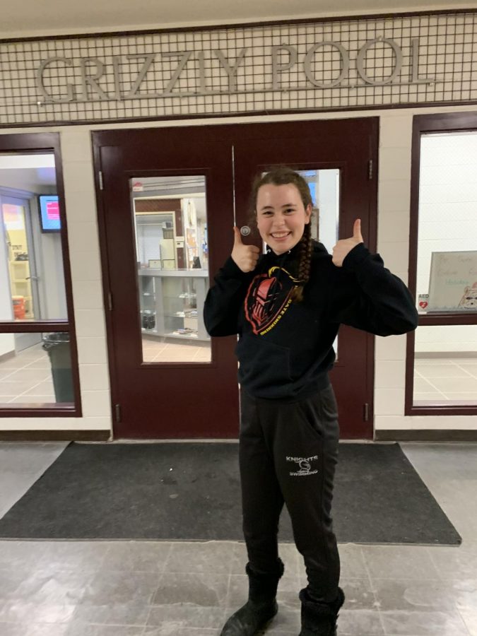 Hazel Seagrave smiles, standing outside the doors to the Grizzly Pool, where the high school swim teams practice.