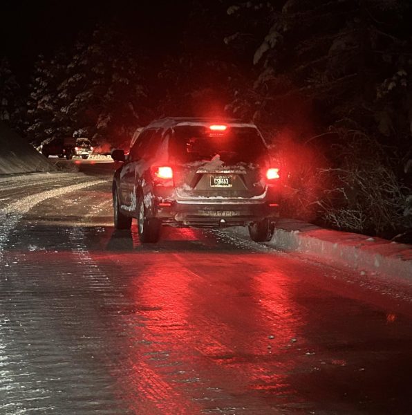 Brake lights reflecting in the mirror-like surface of Snowbowl road. Photo by Will Hansen. 